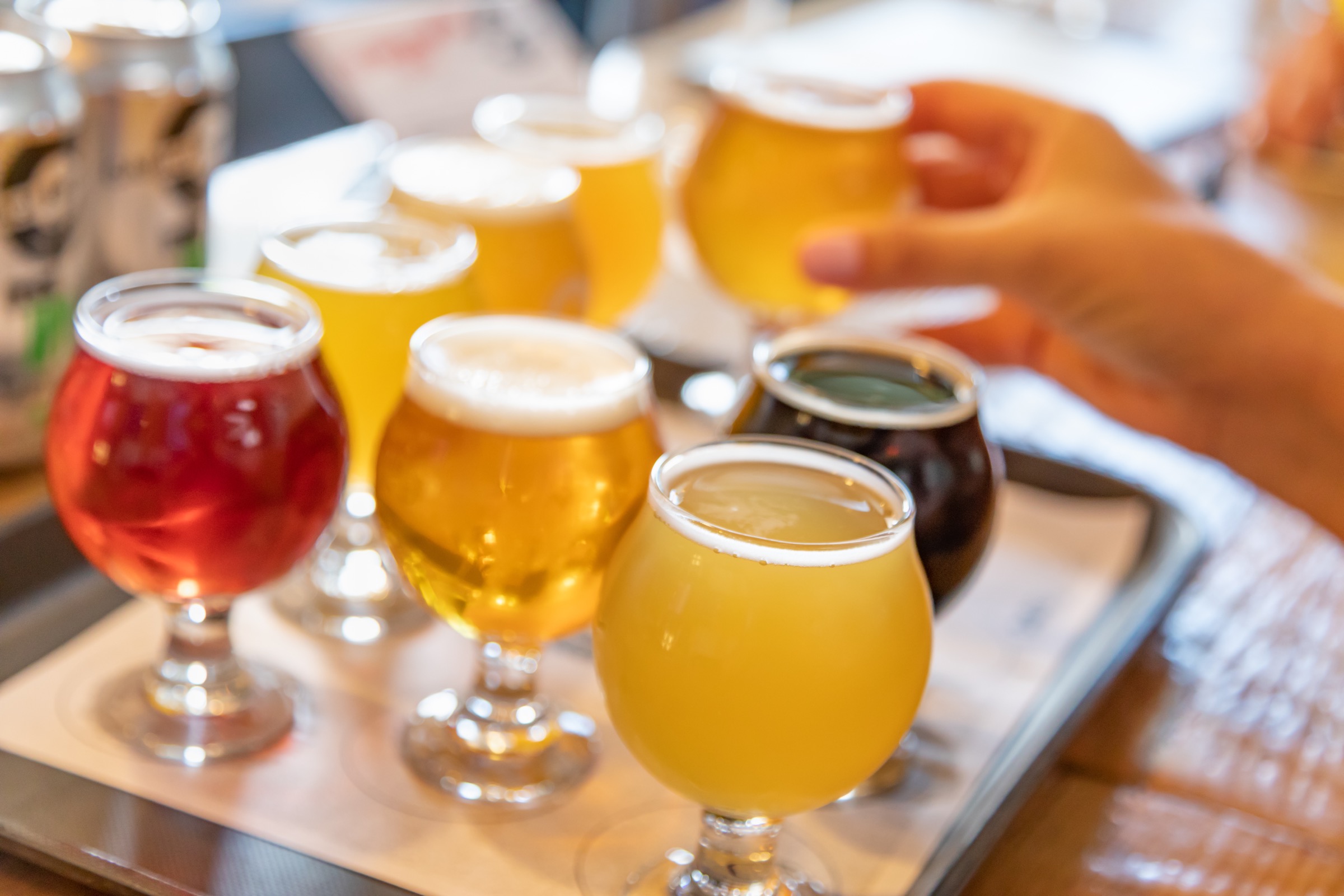 Hand reaching for a beer on the table around other beers