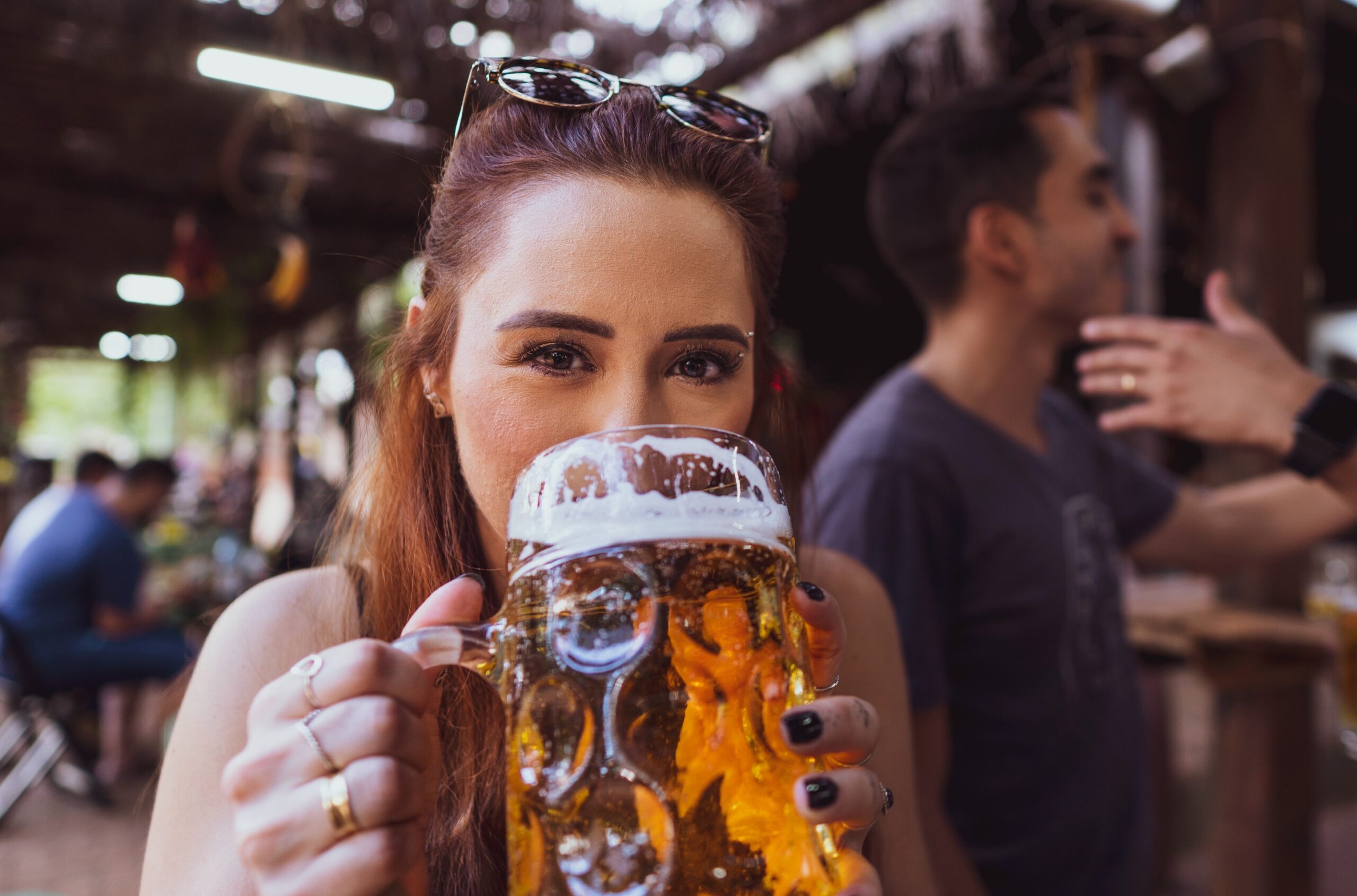 A woman drinking beer from a very large glass mug